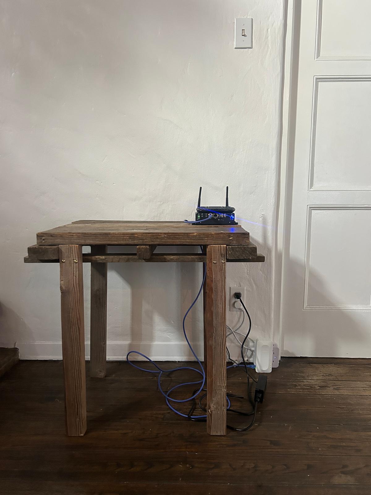 image of a mini pc with antennaes and mini keyboard on top of a small wooden table