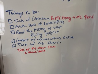 A whiteboard with a to-do list including tasks like talking with a librarian, asking about lanternflies, and reading history, written in blue and red markers.